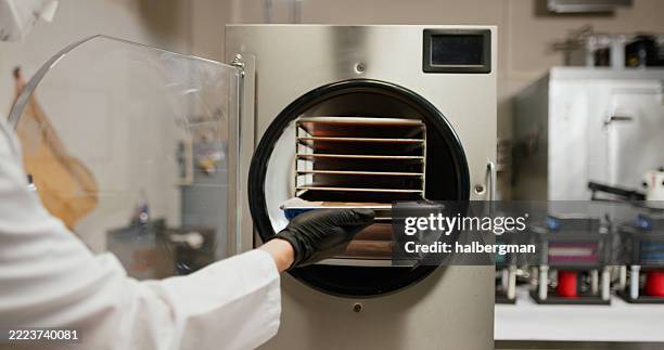 handschuh von hand lädt nasses haschisch in den gefriertrockner - vakuumkammer stock-fotos und bilder