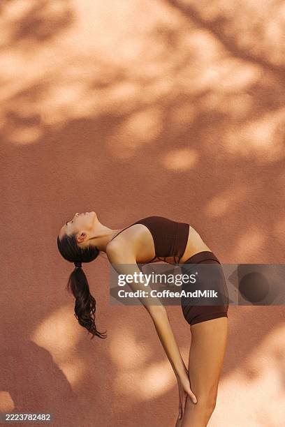donna che pratica yoga all'aperto in una posa graziosa di piegamento all'indietro in una giornata di sole - piegarsi allindietro foto e immagini stock