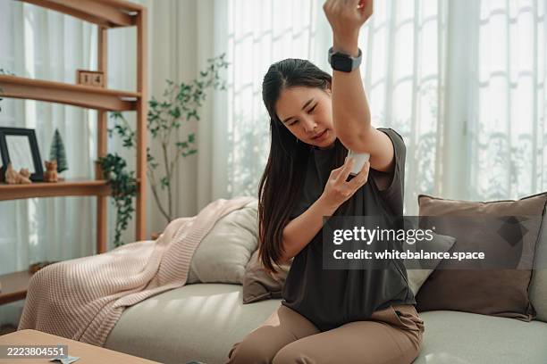 asian woman using cgm device on her arm to check her blood sugar level - fühler stock-fotos und bilder
