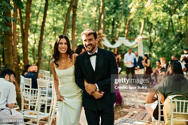 pareja feliz caminando por el pasillo en la ceremonia de boda al aire libre en el bosque - boda fotografías e imágenes de stock