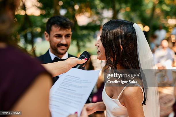 bride speaking into microphone during wedding ceremony in the woods - wedding vows stock pictures, royalty-free photos & images