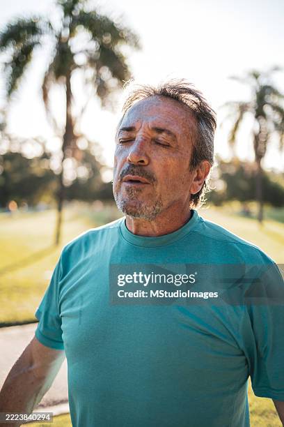 senior man breathing hard after exercising in a park - exhaling stock pictures, royalty-free photos & images