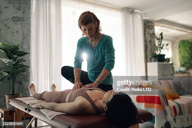 terapeuta que realiza un tratamiento de reiki en el estómago del paciente en el entorno doméstico - reiki fotografías e imágenes de stock