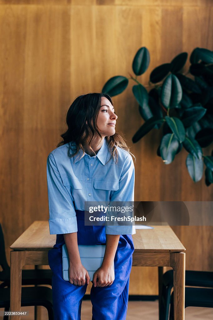 Stylish Woman Sitting Casually in a Modern Indoor Setting with Wooden Decor