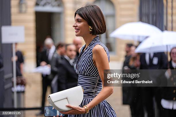 Guest wears a sleeveless mini dress featuring a deep V-neckline and a fitted bodice with a flared skirt. The backless dress is patterned with...