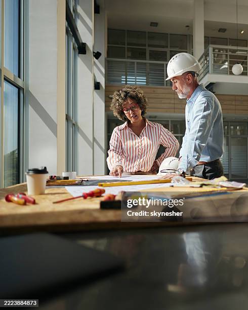 mature architects working on plans at construction site. - real estate developer stock pictures, royalty-free photos & images