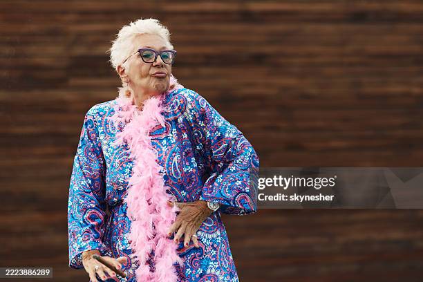 carefree senior woman with a cigar dancing against brown background. - eccentric stock pictures, royalty-free photos & images