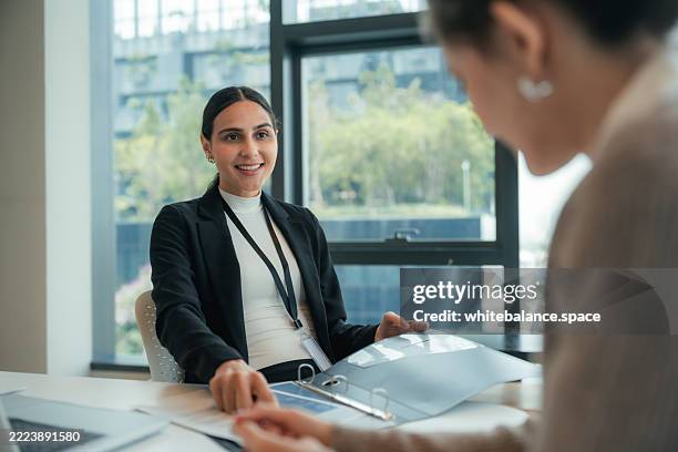 junge berufseinsteigerin, die sich bei ihrem ersten vorstellungsgespräch selbstbewusst dem manager im besprechungsraum vorstellt - sich verschönern stock-fotos und bilder