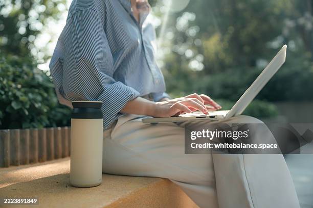 happy female employee sitting outdoors with her laptop, eagerly researching in her free time for an upcoming project - reusable stock pictures, royalty-free photos & images