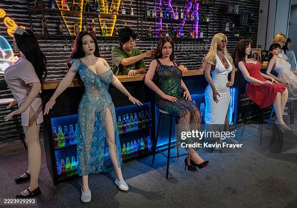 Staff member adjusts the hair of a silicone sex doll, also known as a love doll, as it is displayed with others in the showroom area at a factory for...