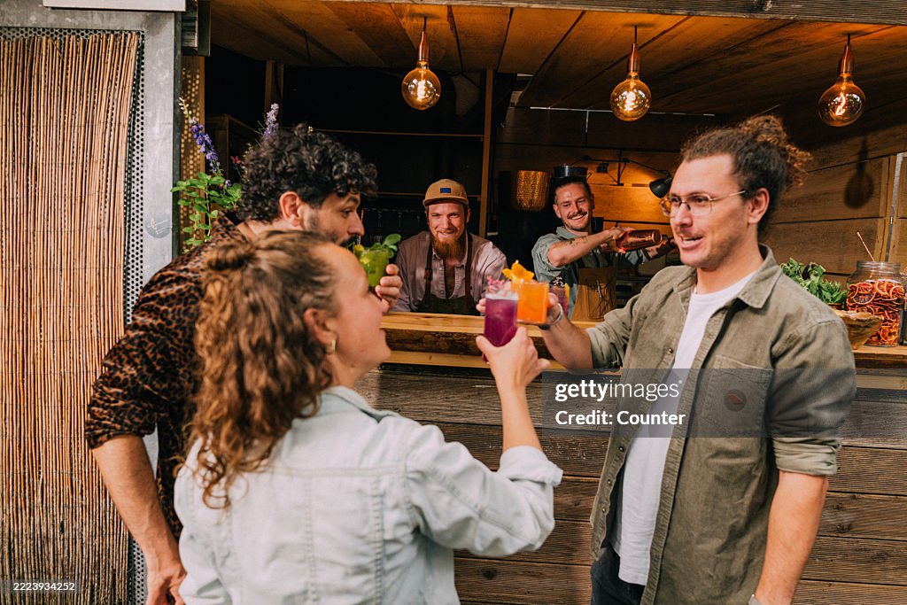 Group of Friends Enjoying Drinks at a Rustic Outdoor Bar Setting