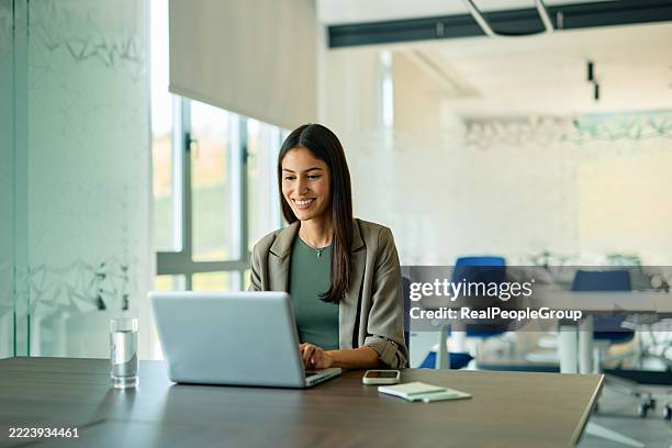 giovane imprenditrice che lavora su laptop in ufficio moderno - figura femminile foto e immagini stock