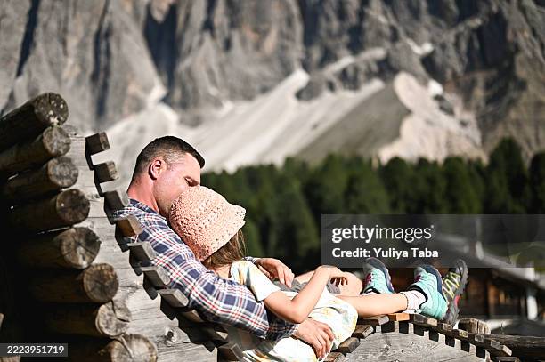 father and daughter relaxing on mountain bench. val di funes in italian dolomites - mountain hut stock pictures, royalty-free photos & images