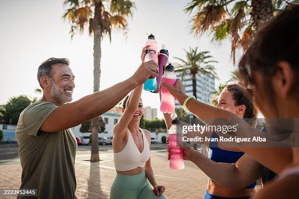 fitness-menschen, die nach dem outdoor-training mit isotonischen getränken feiern - energydrink stock-fotos und bilder