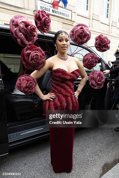 Cardi B is seen wearing a ruby-red corseted gown from Rahul Mishra's Fall 2025 collection, featuring a cinched waist and dramatic roselike tendrils...