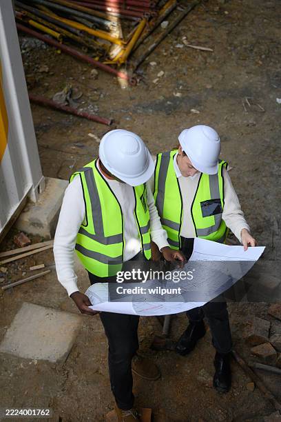 profesionales de la construcción revisando planos en el lugar de trabajo activo - movimiento de tierras fotografías e imágenes de stock