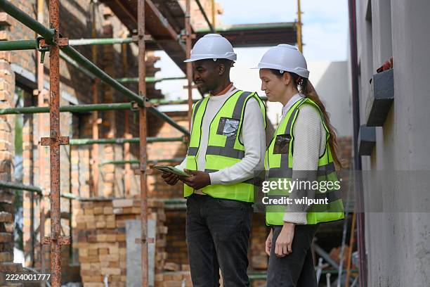 ingenieros revisando los planos de construcción en una obra con andamios - movimiento de tierras fotografías e imágenes de stock