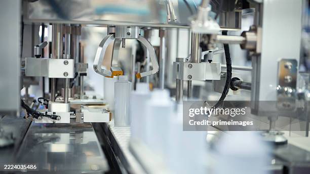 produktionslinie für pharmazeutische oder kosmetische produkte mit automatisiertem spender für kleine plastikflaschen | präzisions-flüssigkeitsabfüllsystem in moderner industrieller verpackungsmaschine - produktionsgerät stock-fotos und bilder