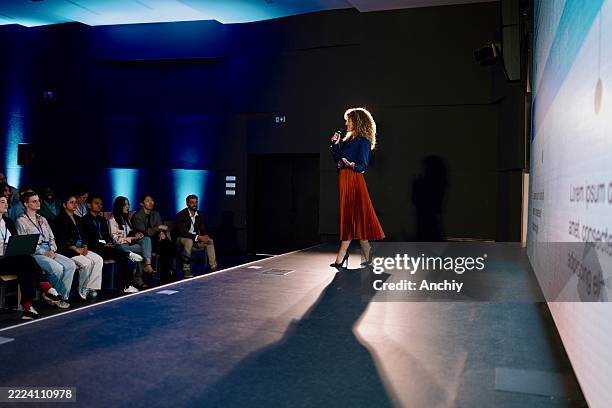 confident speaker presenting at modern technology conference in professional venue - discorso programmatico foto e immagini stock