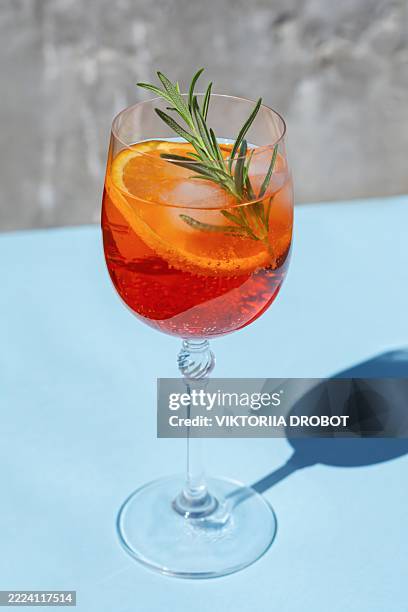 spritz cocotail in a wine glass on a blue background. summer alcoholic beverage, refreshing italian aperitif. - aperol spritz stock pictures, royalty-free photos & images