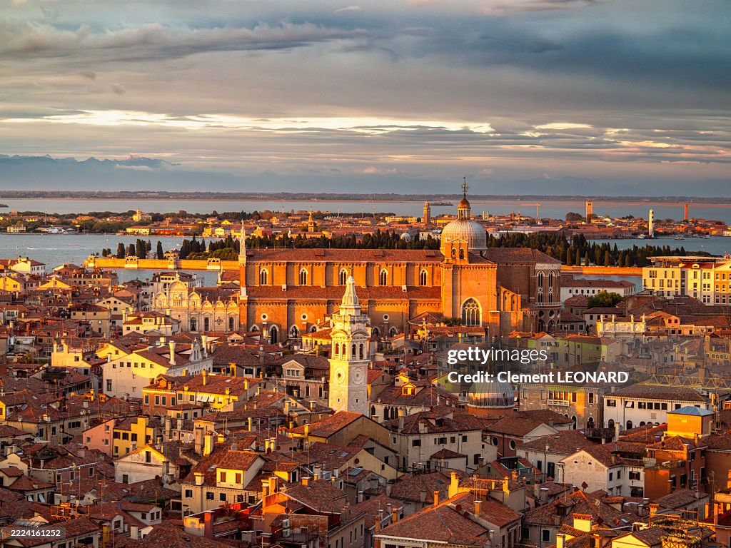 Aerial view of the Castello district and the Basilica dei Santi Giovanni e Paolo medieval gothic church glowing red at sunset, with the San Michele island and Murano in the background, UNESCO World Heritage Site - Veneto - Italy.