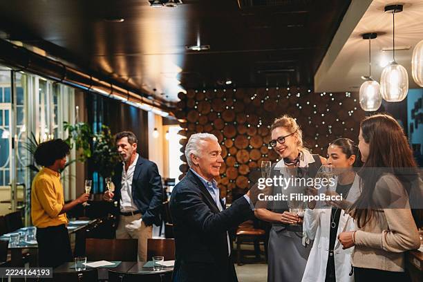 uomini d'affari che brindano con flute di champagne a un evento aziendale in un ristorante - happy hour foto e immagini stock