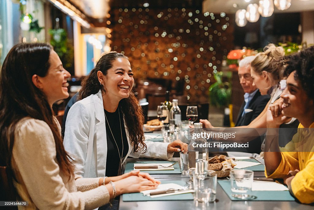 Amigos riendo y disfrutando de una cena juntos en un restaurante