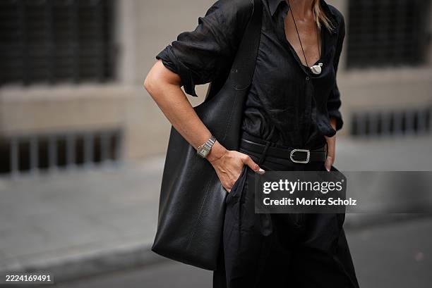 Mirja Klein is seen wearing a black flowing linen shirt with long sleeves, shirt collar and relaxed silhouette from Massimo Dutti; a black wide leg...