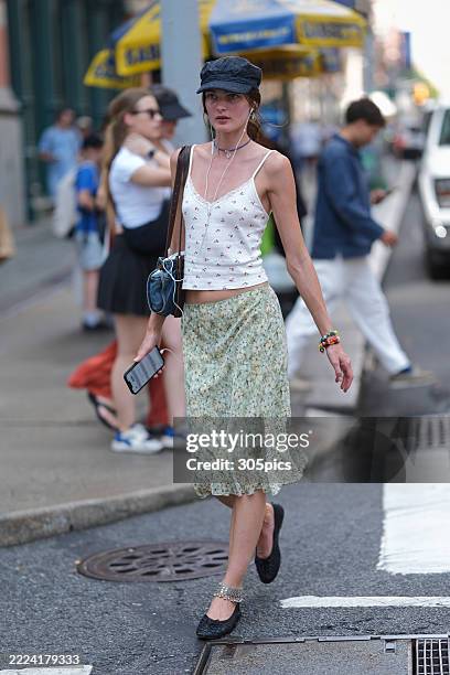Nana Abramova wears a navy baker boy Ralph Lauren cap, white cherry print top, green floral print midi skirt, black ballet flats, a Miu Miu bag and...