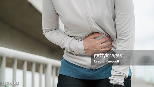asian woman having stomachache while exercise - menstruation hälsovård och medicin bildbanksfoton och bilder