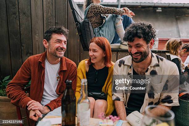 happy friends enjoying outdoor social gathering and sharing laughter together - café esplanada imagens e fotografias de stock