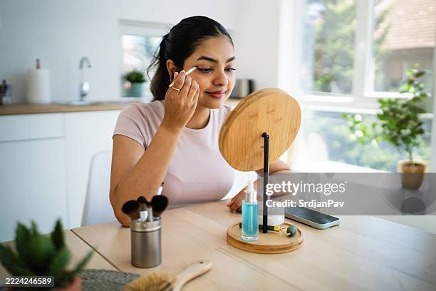 young indian woman is doing her makeup at home - eyeshadow stock pictures, royalty-free photos & images