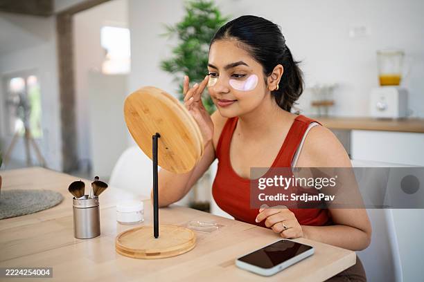 beautiful young woman applying hydrogel under-eye recovery patches at home - eye patch stock pictures, royalty-free photos & images