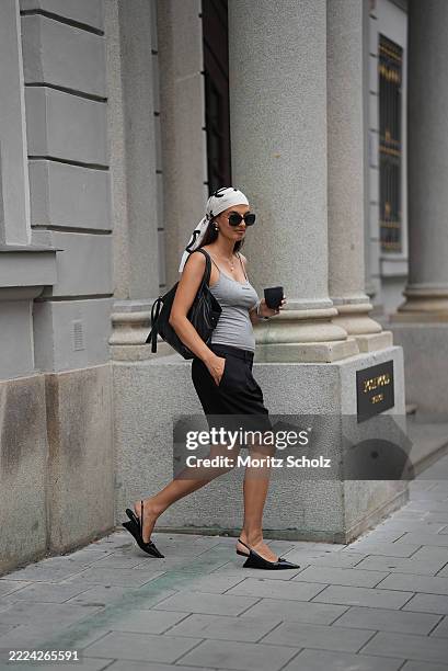 Anna Winter is seen wearing black Bobby Bermuda shorts with relaxed fit and pleat from Black Palms; a light grey ribbed racer tanktop with black logo...