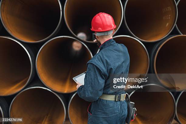 rear view of an engineer using a pipe measuring device for a gas pipeline and digital tablet - oil field stock pictures, royalty-free photos & images
