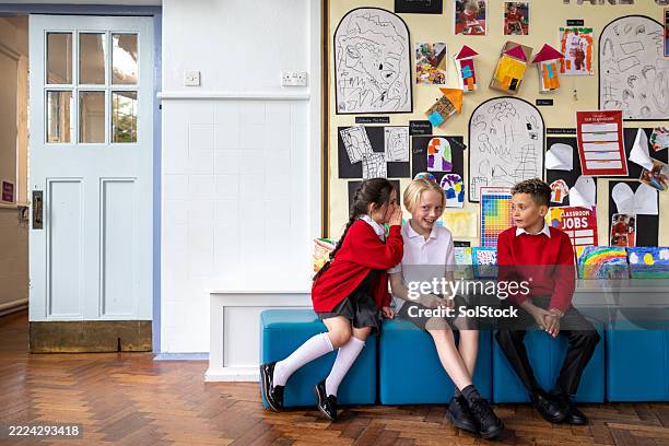 school children whispering gossip - school uniform stock pictures, royalty-free photos & images