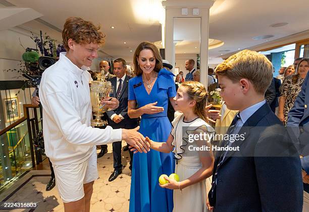 In this handout photo issued by AELTC, Jannik Sinner of Italy holds the Gentlemen's Singles Trophy and shakes hands with Princess Charlotte of Wales...