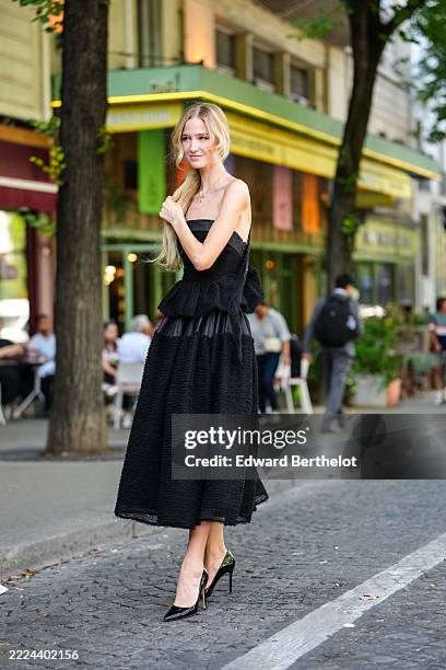 Guest wears a strapless black dress featuring a textured, boucle-like fabric. The dress has a fitted bodice with a peplum detail at the waist and a...