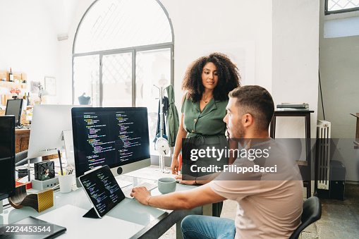 Computer programmers working together on code in modern office Computer programmers working together on code in modern office