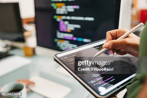 Software developer writing code on a digital tablet with a stylus pen Software developer writing code on a digital tablet with a stylus pen