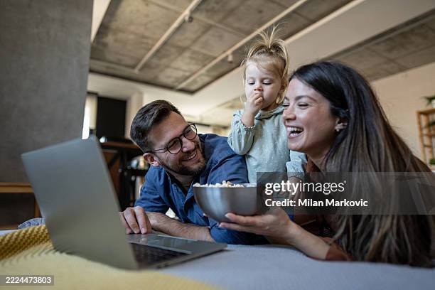 familie genießt einen filmabend mit popcorn und laptop - family movie night snacks stock-fotos und bilder