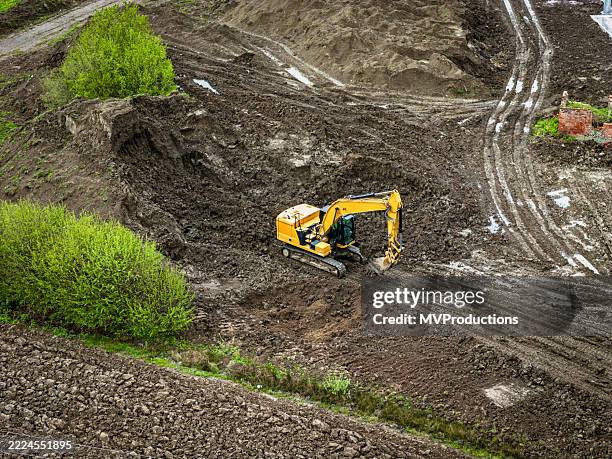 excavadora operando en un sitio de construcción fangoso - movimiento de tierras fotografías e imágenes de stock
