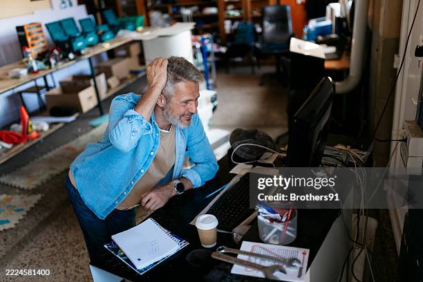 engineer working on computer in messy workshop, scratching head - prototype stock pictures, royalty-free photos & images