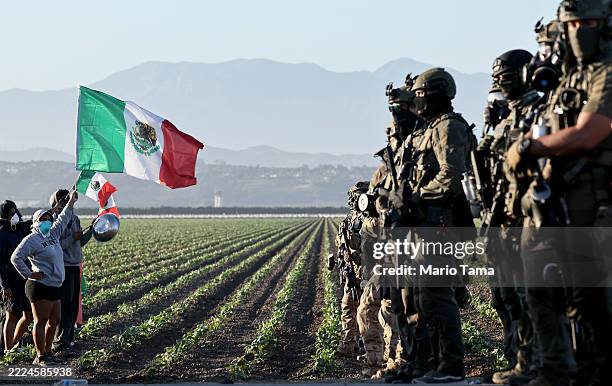 Federal agents block people protesting an ICE immigration raid at a nearby cannabis farm on July 10, 2025 near Camarillo, California. Protestors...