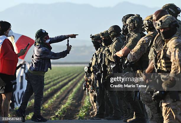 Federal agents block people protesting an ICE immigration raid at a nearby cannabis farm on July 10, 2025 near Camarillo, California. Protestors...