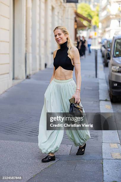 Christine Wuerfel-Stauss / Christine Würfel-Stauss wears vlack cropped Alaïa Alaia top and shoes, turquoise Loewe pants, Hermes bag during the Haute...