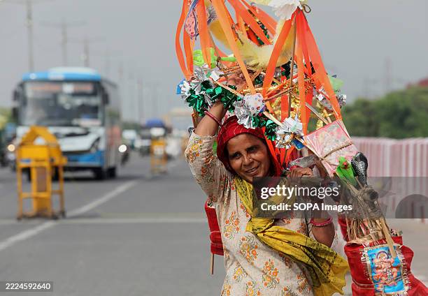 Kanwariyas woman known as a Lord Shiva devotee carries a sacred Ganga Jal collected from Haridwar walks towards her home town temple seen near...