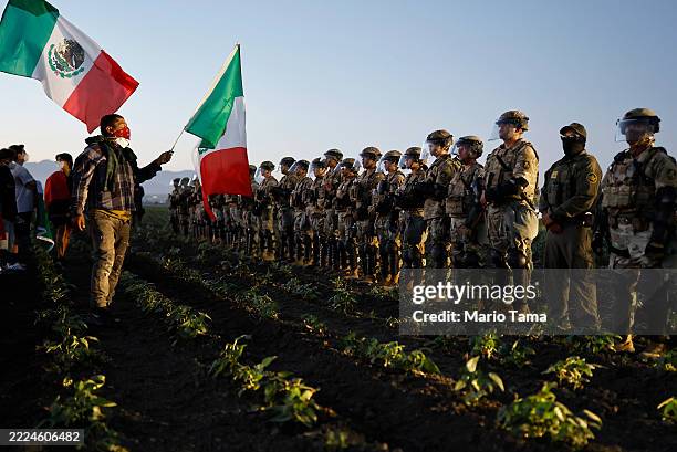 National Guard members and a federal agent block people protesting an ICE immigration raid at a nearby licensed cannabis farm on July 10, 2025 near...