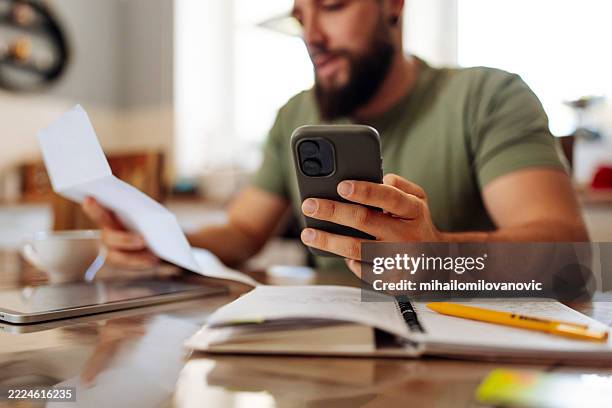 mann, der seine finanzen mit dem smartphone überprüft - finanzplanung stock-fotos und bilder