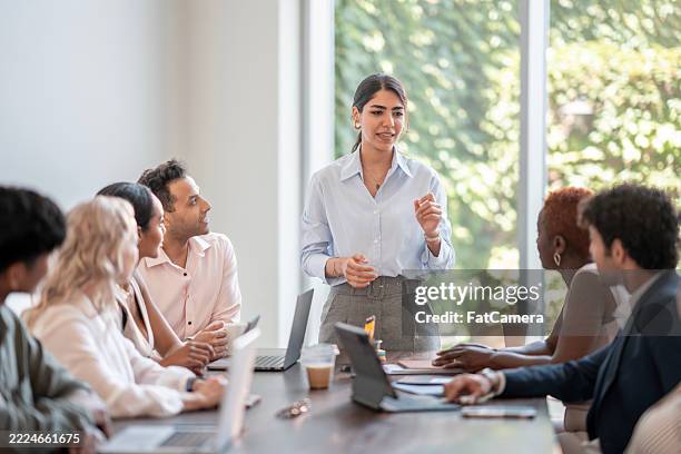 young professional leading an inclusive team meeting in a modern office - chairperson stock pictures, royalty-free photos & images